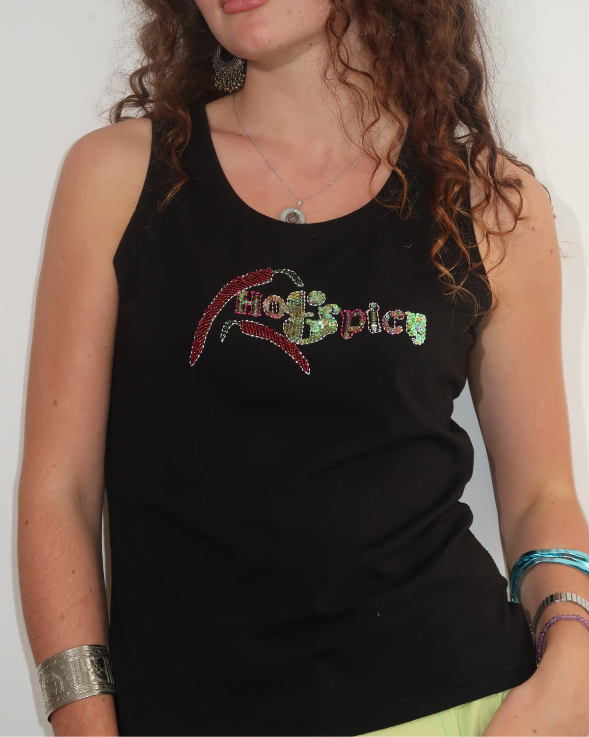 A person wearing a black vintage tank top with 'hot & spicy' embellished and vintage christian dior sport lime green cargo pants