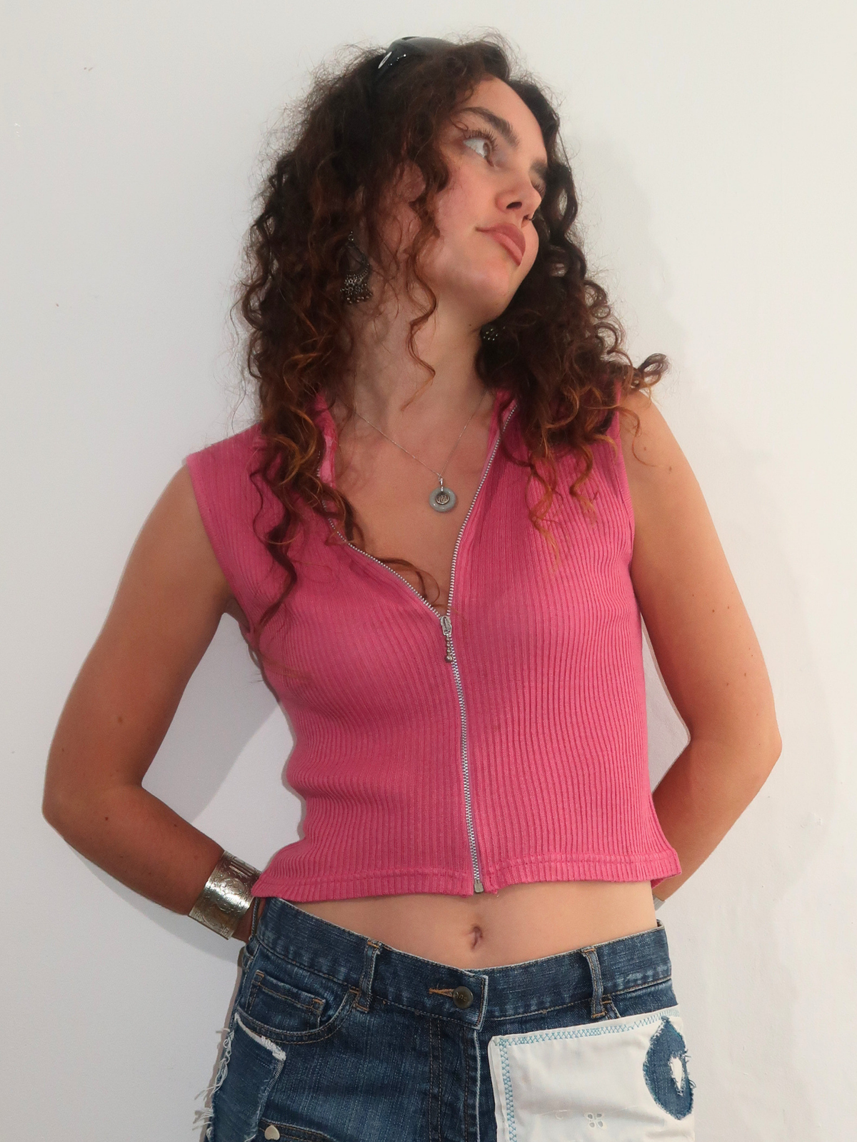 model wears pink zip up vintage top with collar and fun fcuk denim skirt against white wall